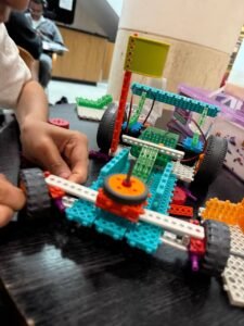 Kids assembling a functional car robot with sensors in a robotics for kids workshop, developing problem-solving skills for ages 6-12.