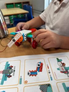 Team of children programming an educational robot with sensors in robotics for kids classes, promoting teamwork for ages 9-14.